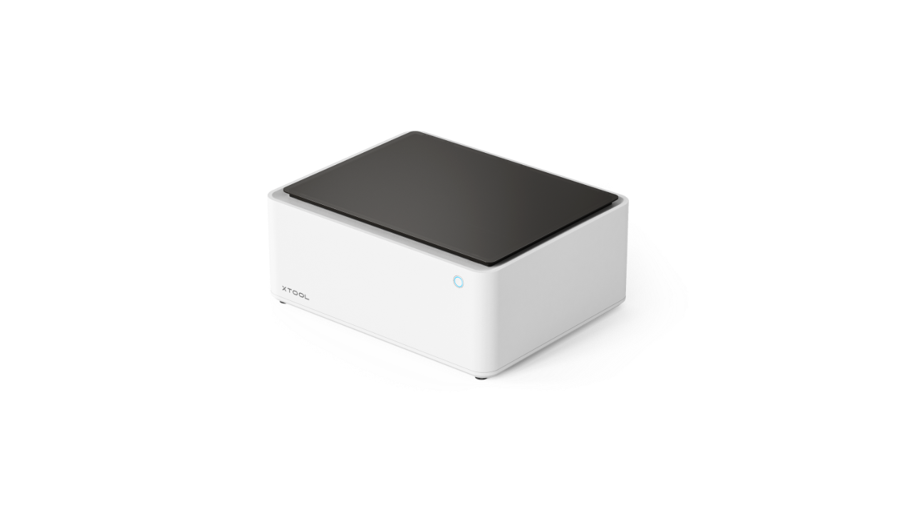 xTool M1 10W Desktop Hybrid Laser- und Schneidemaschine in geschlossener Ansicht, schräg von vorne fotografiert, mit weißem Gehäuse und schwarzer Abdeckung.