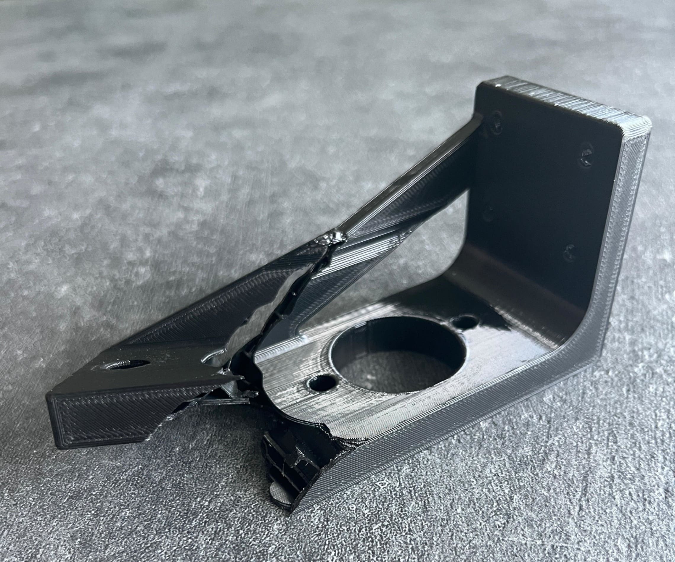 Gebrochenes schwarzes Kunststoff-Bauteil aus 3D-Druck mit sichtbaren Bruchstellen